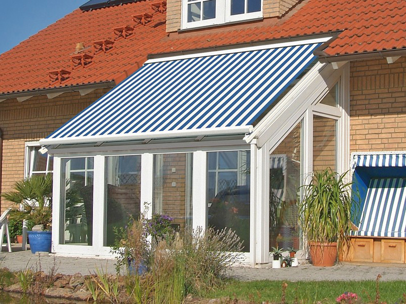 Großes Haus mit blau/weiß gestreifter Glasdachmarkise Großes Haus mit blau/weiß gestreifter Glasdachmarkise