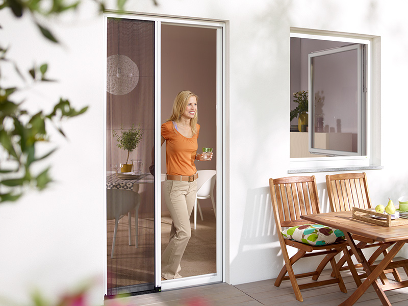 Frau öffnet die Insektenschutzgitter Schiebetür Frau öffnet die Insektenschutzgitter Schiebetür