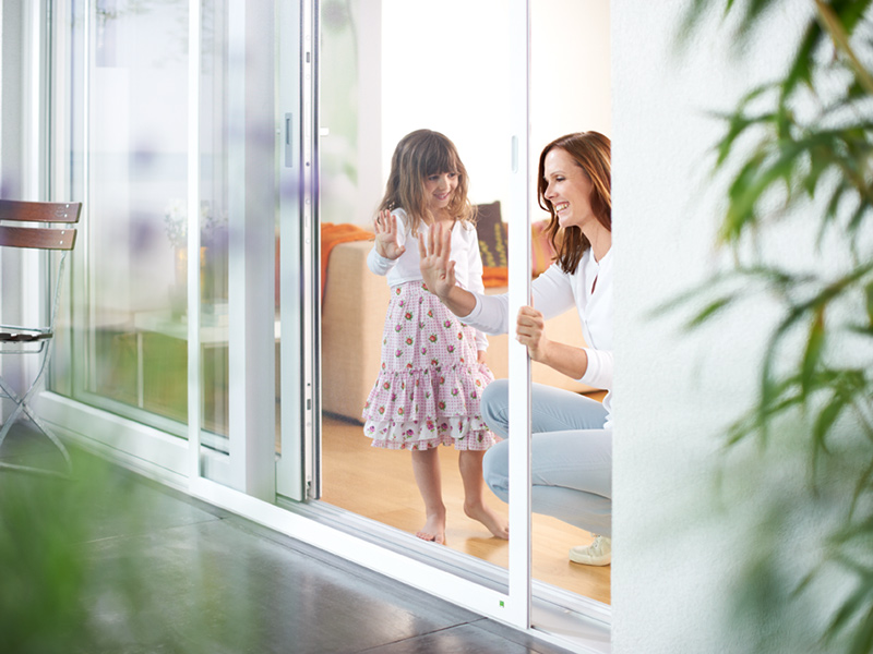 Mutter und Tochter an der Insektenschutzgitter Schiebetür Mutter und Tochter an der Insektenschutzgitter Schiebetür
